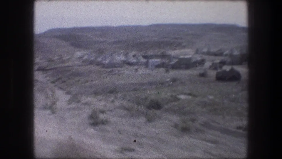 1976 8mm view near Bethlehem showing an arid valley, dirt tracks, scrub, and a small tented encampment in the distance.