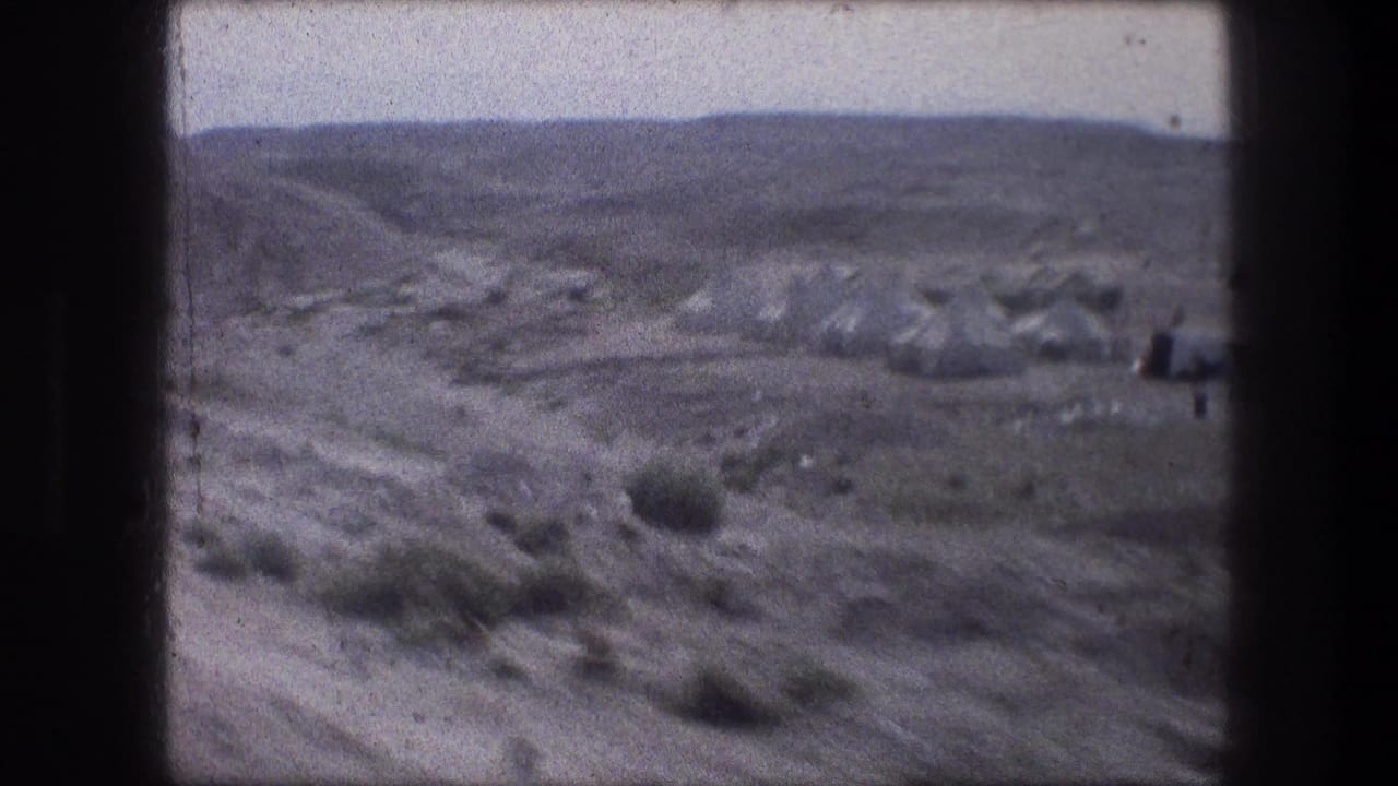 1976 Bethlehem-area home-movie frame with a dirt road, scattered tent-like shelters, scrub, and low barren hills.