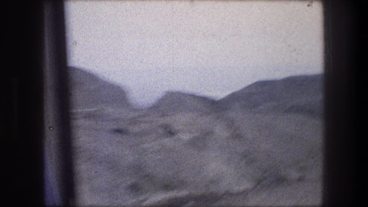 Dry hills and pale sky seen through 8mm film-frame borders.