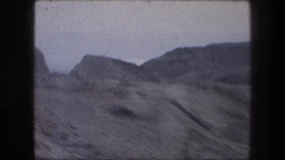 Bethlehem-area 8mm frame showing rugged mountain ridges and dry open ground, with motion softness and film grain.