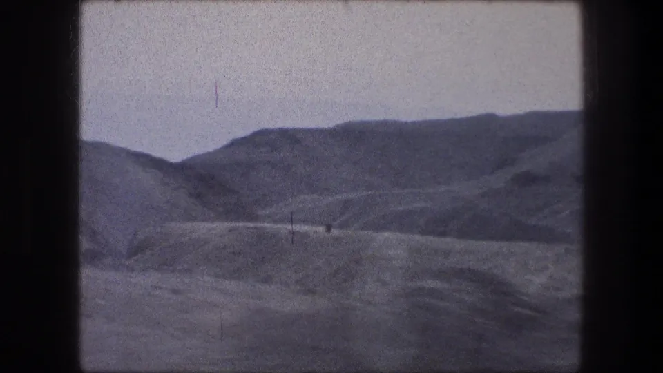 Bethlehem metadata frame showing dry hills, faint track-like lines, and a broad pale sky in vintage 8mm color.
