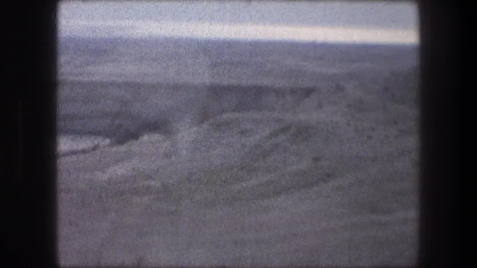 1976 home-movie view near Bethlehem showing flat, barren ground and distant hills through a car window.