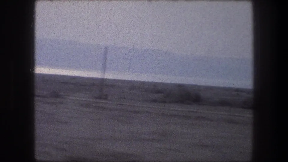 Car-window view of a sparse landscape near Bethlehem with a low horizon and vintage 8mm grain.