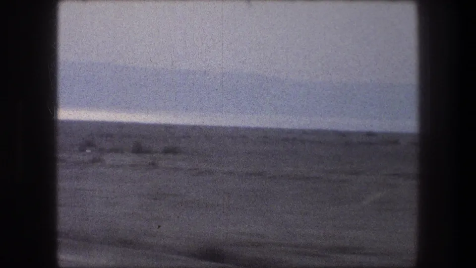 Late-frame 1976 car-window view near Bethlehem, showing empty terrain, a distant ridge, and muted 8mm color.