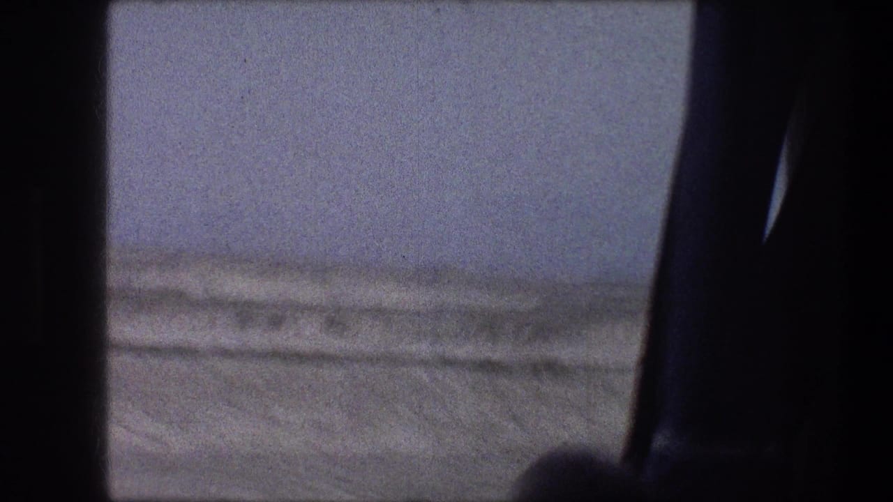 Snowy roadside landscape seen through a dark vehicle window frame.