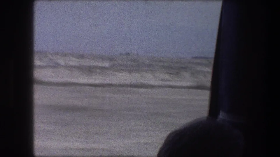 1976 8mm car-window view near Bethlehem, Israel, with snow-toned ground, overcast sky, and a partial interior silhouette.