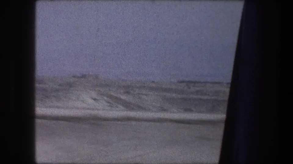 1976 8mm travel frame near Bethlehem, Israel, showing a snowy roadside through a vehicle window divided by a dark pillar.
