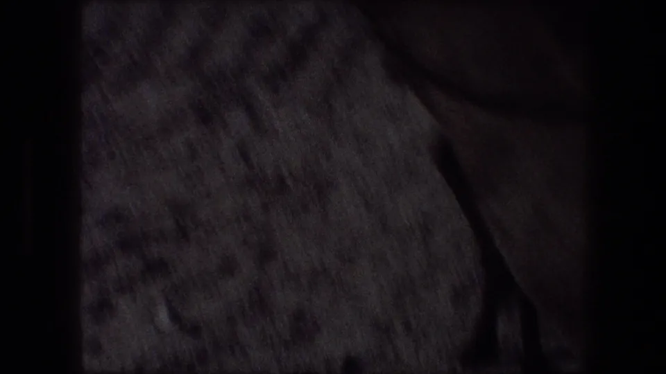 Close, underexposed 8mm frame with textured foreground and obscured desert detail from the Bethlehem-area travel footage.