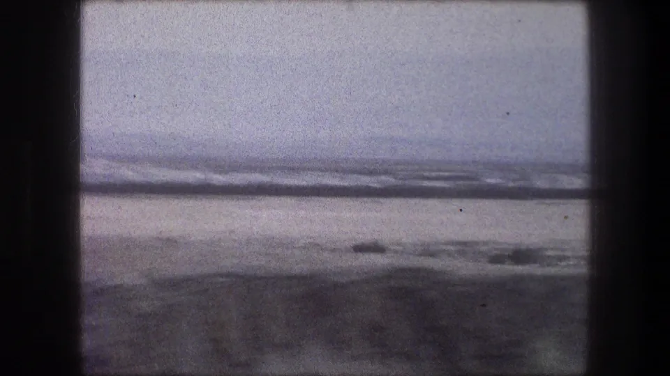 1976 Bethlehem 8mm frame of open sandy terrain and a hazy horizon, with dark film borders visible from the scan.