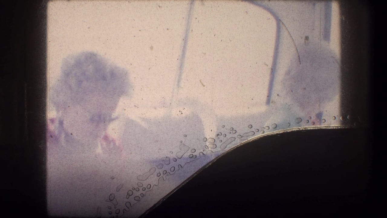 Two seated passengers faintly visible through a bus interior window area.