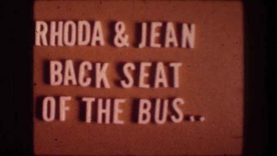1976 8mm home-movie title card from Bethlehem, Israel, with white text on orange reading Rhoda and Jean back seat of the bus.