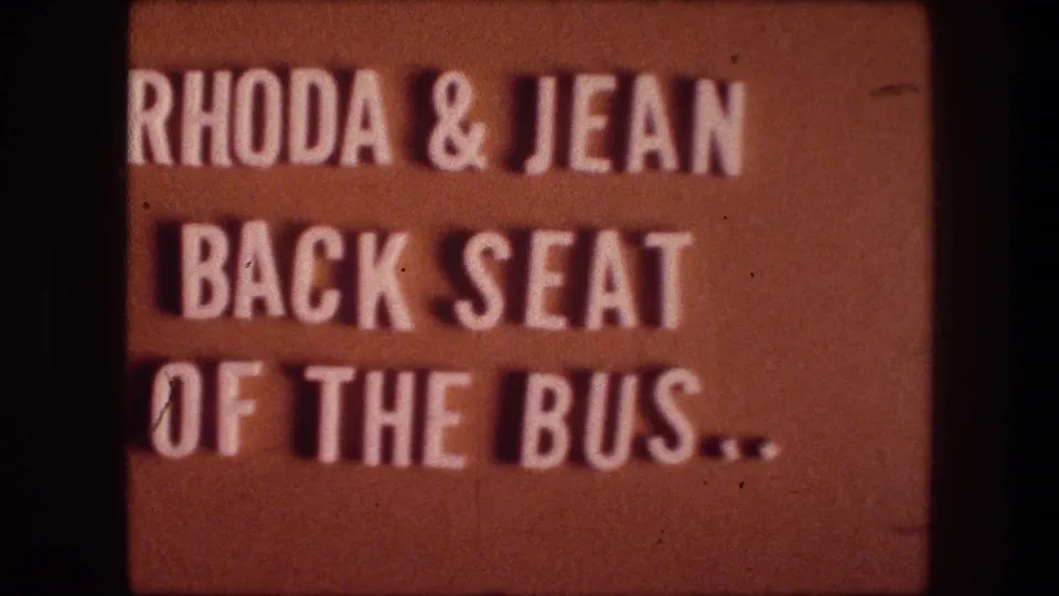Final sampled 1976 8mm title-card frame from Bethlehem, Israel, with cropped white text naming Rhoda and Jean and the bus back seat.