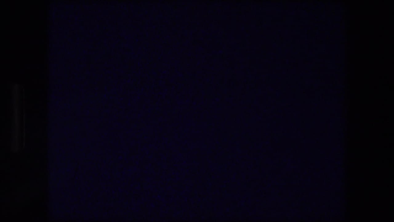 Mostly dark frame with faint blue tint and film edge shadows.