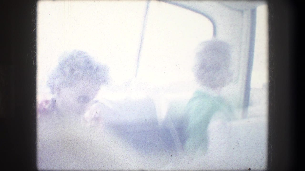 Two women seated on a bus, partly washed out by bright window light.