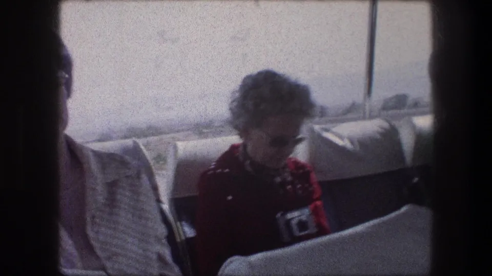 1976 Bethlehem, Israel travel frame showing a woman handling a small camera from a bus seat, with another passenger partly in view.