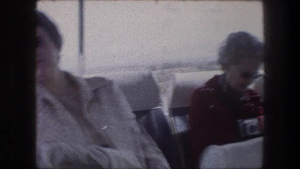1976 Bethlehem, Israel home-movie frame of two adult women seated on a bus with washed bright window light behind them.