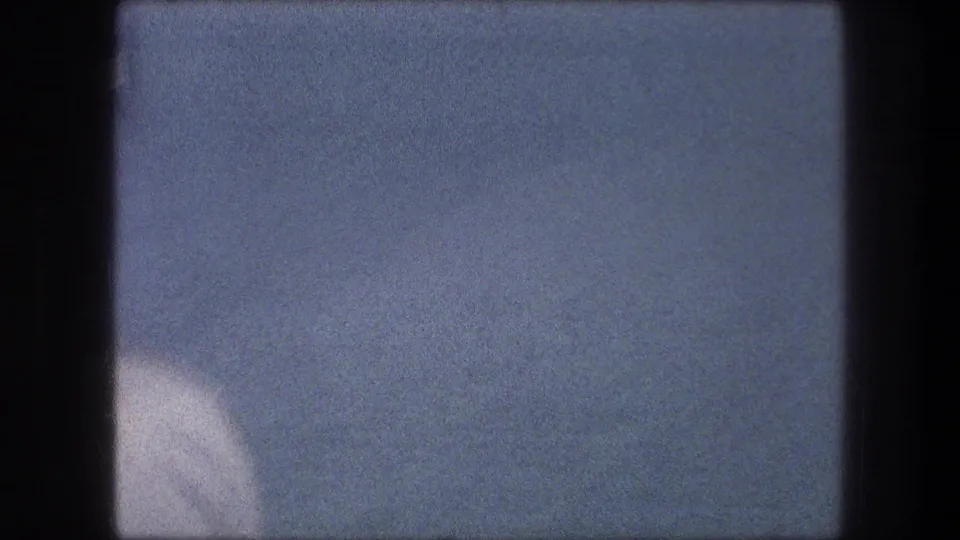 Soft 8mm frame from the 1976 Bethlehem reel, with a pale water-like surface and faint distant shoreline.