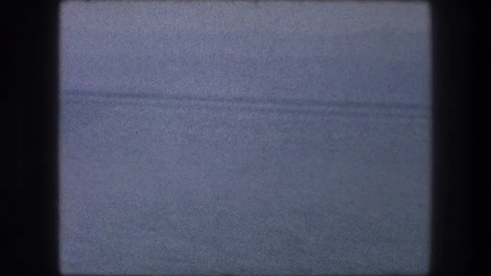 1976 8mm Bethlehem frame showing a blue-gray water-like expanse and faint far shore through grain and blur.