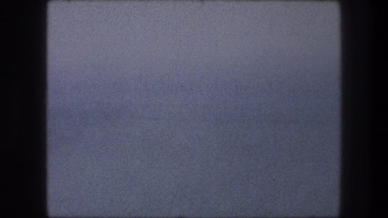 Mostly pale blue sky with dark 8mm frame borders and visible film grain.