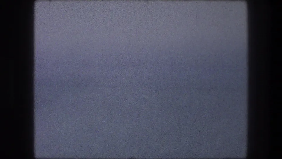 A 1976 8mm home-movie frame from Bethlehem, Israel showing mostly pale blue sky, soft exposure, grain, and dark gate edges.