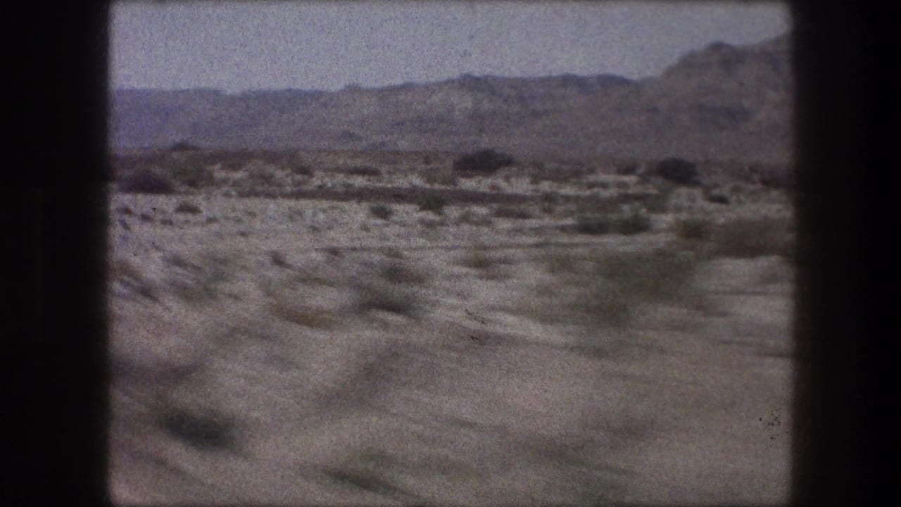 Bethlehem-area 1976 home-movie frame with scrubby ground, scattered small structures, and rocky hills beyond.