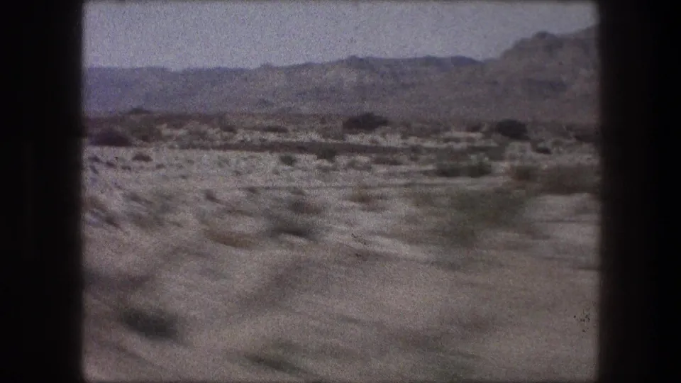 Bethlehem-area 1976 home-movie frame with scrubby ground, scattered small structures, and rocky hills beyond.