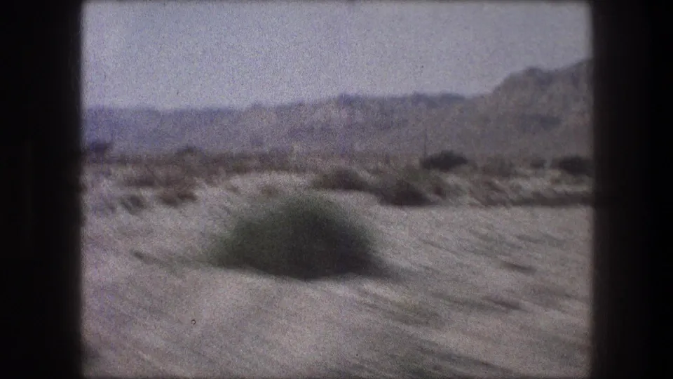 1976 Bethlehem-area road view with motion-blurred brush in the foreground and dry hills in the background.
