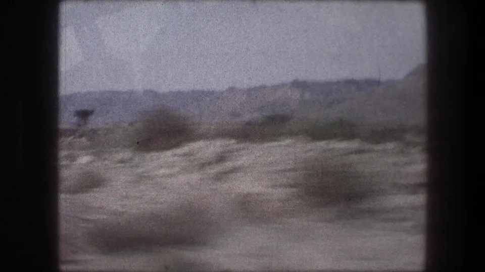 Moving 8mm frame from Bethlehem, Israel in 1976, with scrub brush streaking past and a low mountain ridge across the horizon.