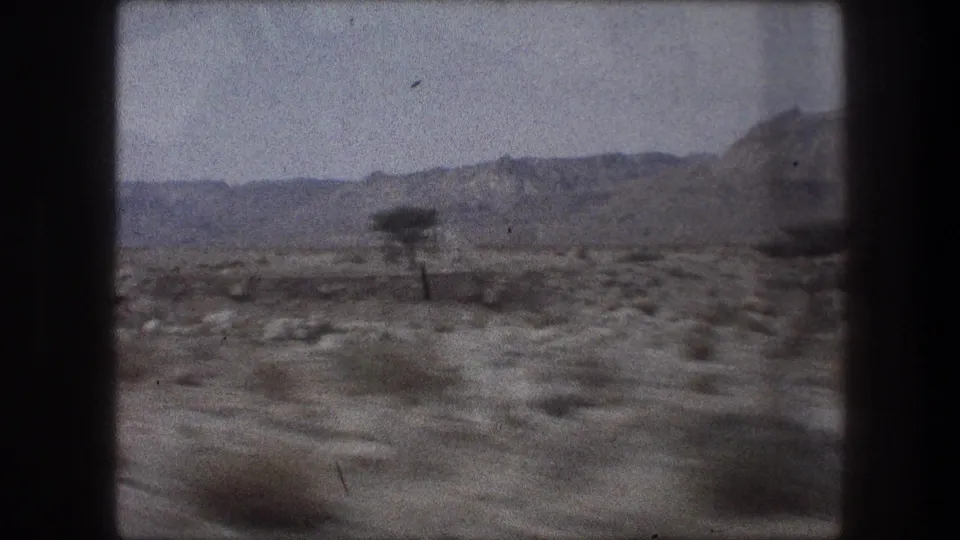 1976 8mm travel frame near Bethlehem, Israel, showing a lone utility pole, desert shrubs, rocky ground, and distant hills.