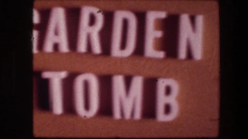 Soft 1976 8mm close-up at the Garden Tomb sign in Jerusalem, showing cropped raised white letters against brown backing.