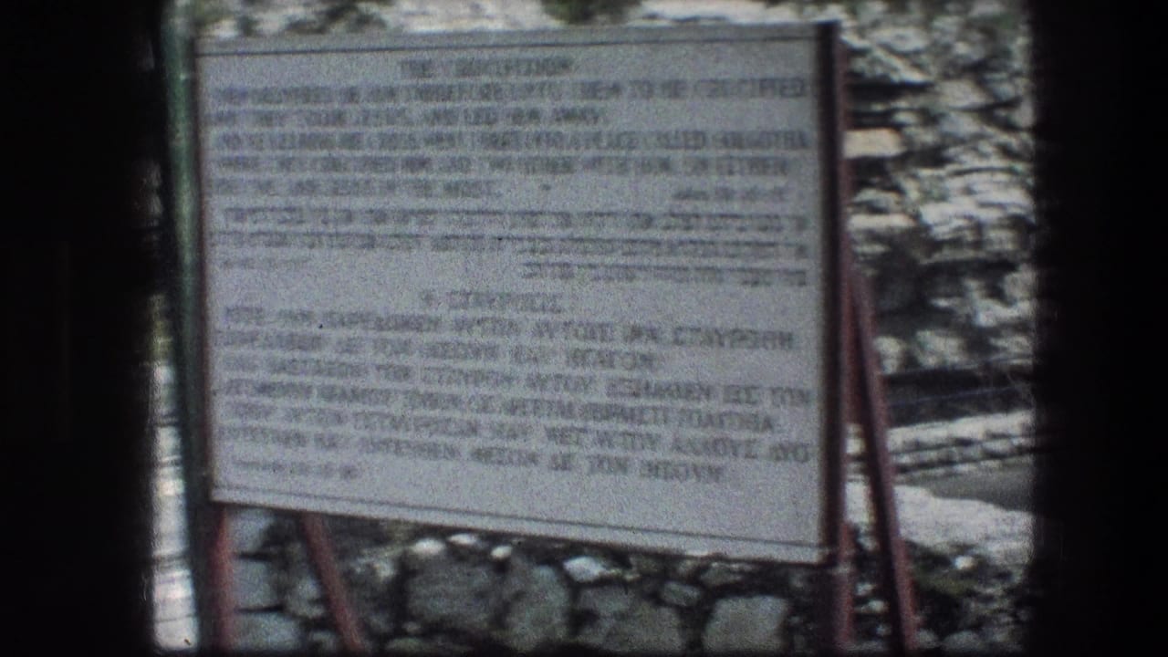 A weathered Garden Tomb information sign stands before stonework and rocky ground in the 1976 Jerusalem home-movie footage.