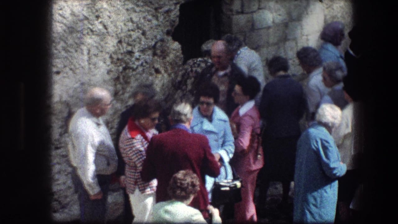 Tourists gather beside a pale stone entrance, seen through a dark surrounding frame.