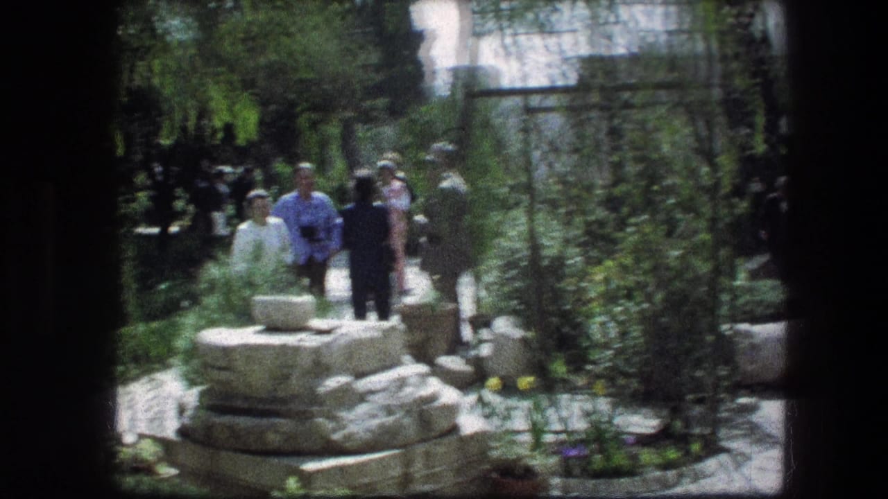 Visitors walking near a stone feature on a shaded garden path.