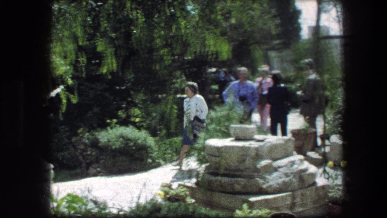 Woman in a white top walks along the Garden Tomb path in Jerusalem with other visitors behind her.