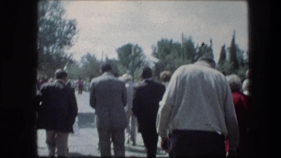 1976 home-movie frame of a mixed adult group walking through the Garden Tomb grounds in Jerusalem.