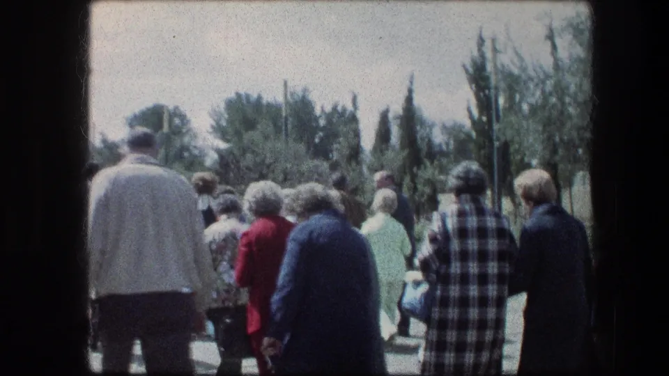 Visitors continue through the Garden Tomb grounds in Jerusalem, seen from behind in soft 1970s 8mm color.