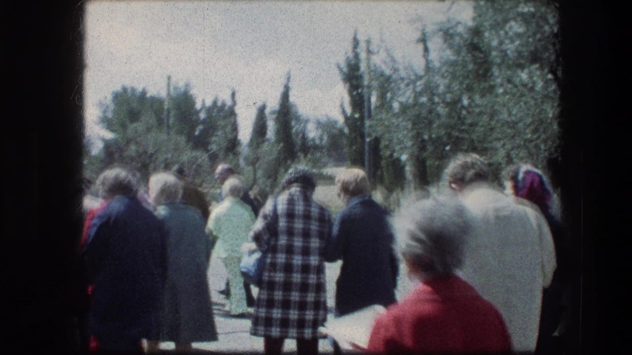 Visitors walking along a garden path with trees and shrubs around them.