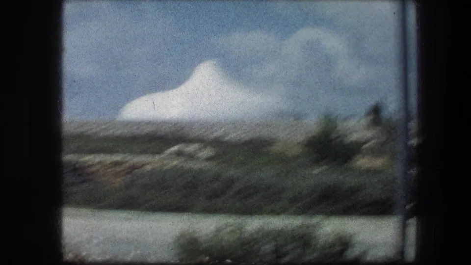 Handheld 8mm view of the white domed structure near the Garden Tomb, softened by motion blur and foreground greenery.