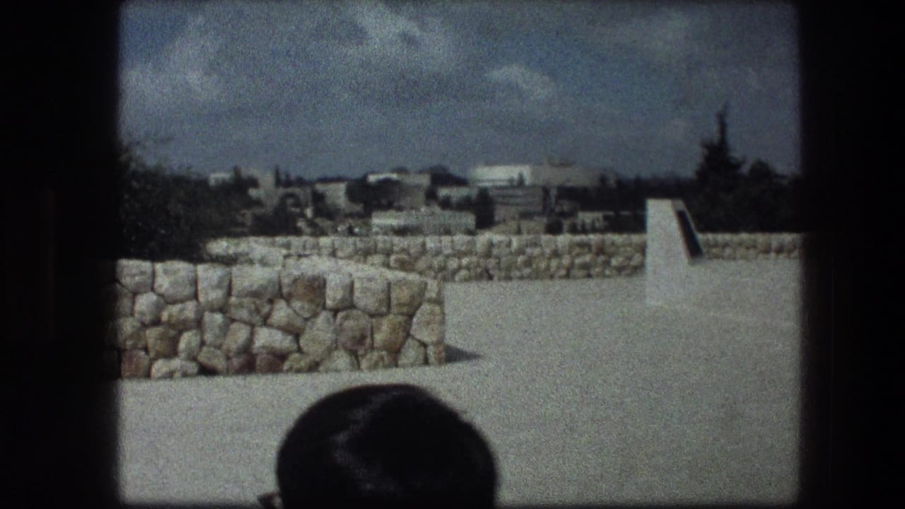 Stone-walled outdoor site with paved walkway and the top of a person's head at the bottom edge.