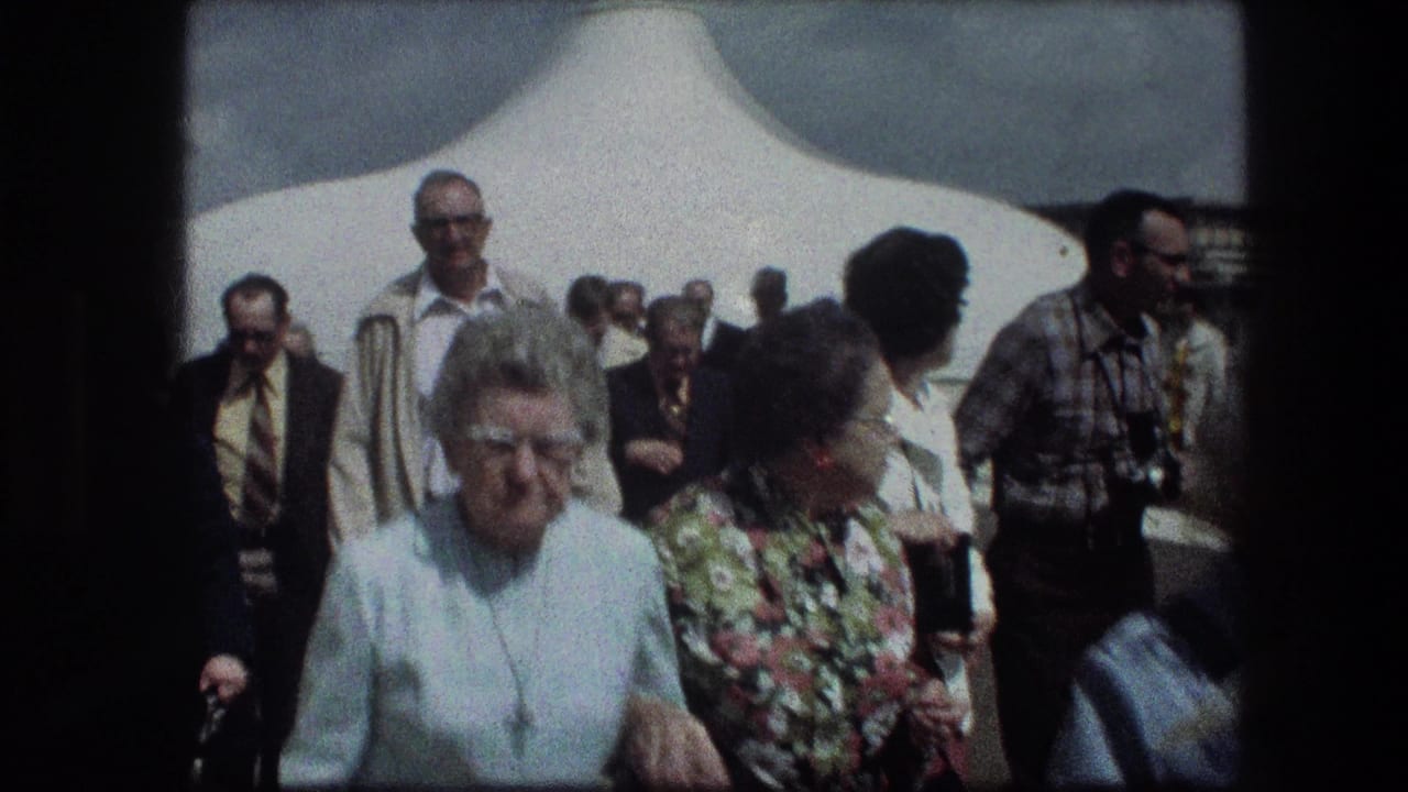Tour group members walk past the camera at the Garden Tomb in Jerusalem, with faces and 1970s clothing visible.