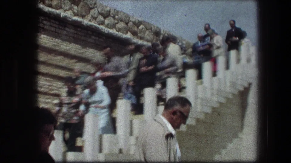 A tour group descends white steps at the Garden Tomb in Jerusalem, captured in a soft handheld 8mm frame.