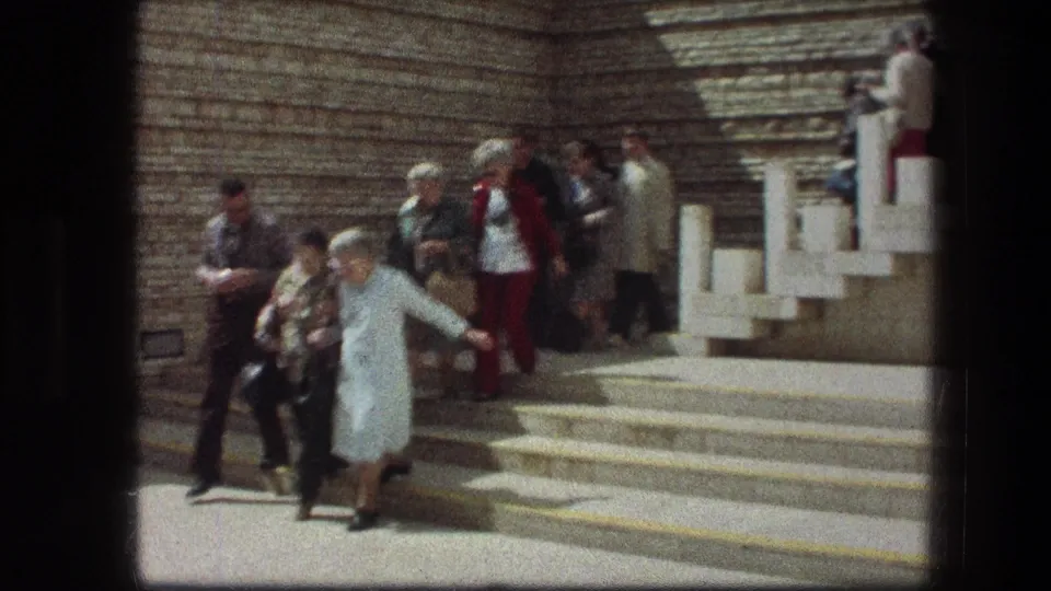 The group continues descending the Garden Tomb steps, with white railings and layered stonework visible behind them.