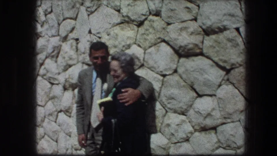 The pair remain posed at the Garden Tomb, with the man facing forward and the older woman turned slightly toward him.