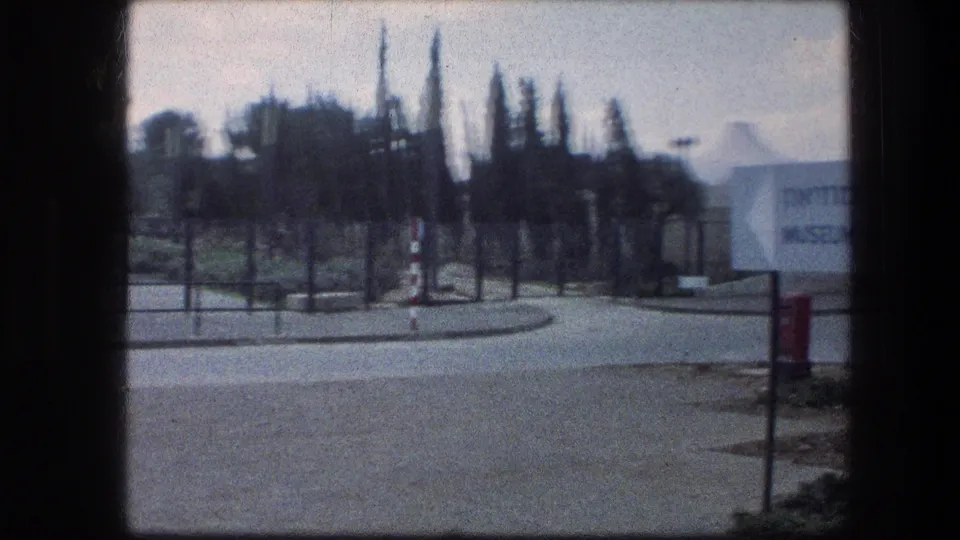 Wider 1976 view of the Garden Tomb entrance area in Jerusalem, showing roadway, trees, fencing, and part of the sign.