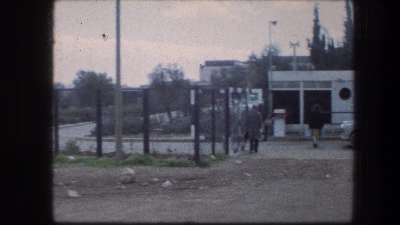 Garden Tomb area in Jerusalem, 1976, with distant visitors walking near a fence and a small white building beside a road.