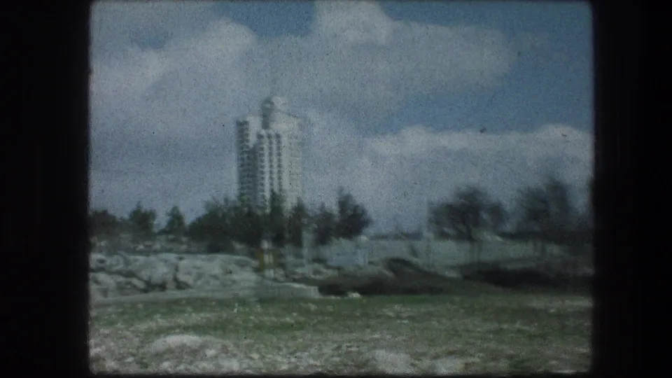 Garden Tomb area in Jerusalem, 1976, with open grass and trees in front of a tall white building beneath a partly cloudy sky.