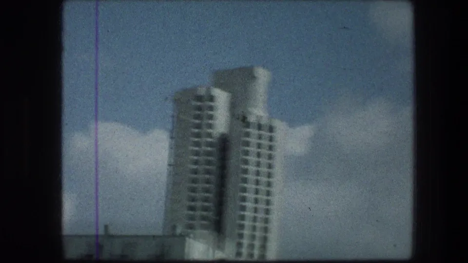 Soft 8mm close view of the white Jerusalem-area tower, with balconies or window rows visible against the sky.
