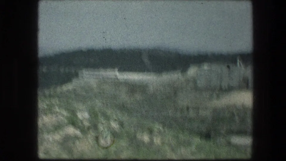 Soft handheld 1976 view near Jerusalem, with rough rocks and grass in the foreground and a dark distant ridge beyond.
