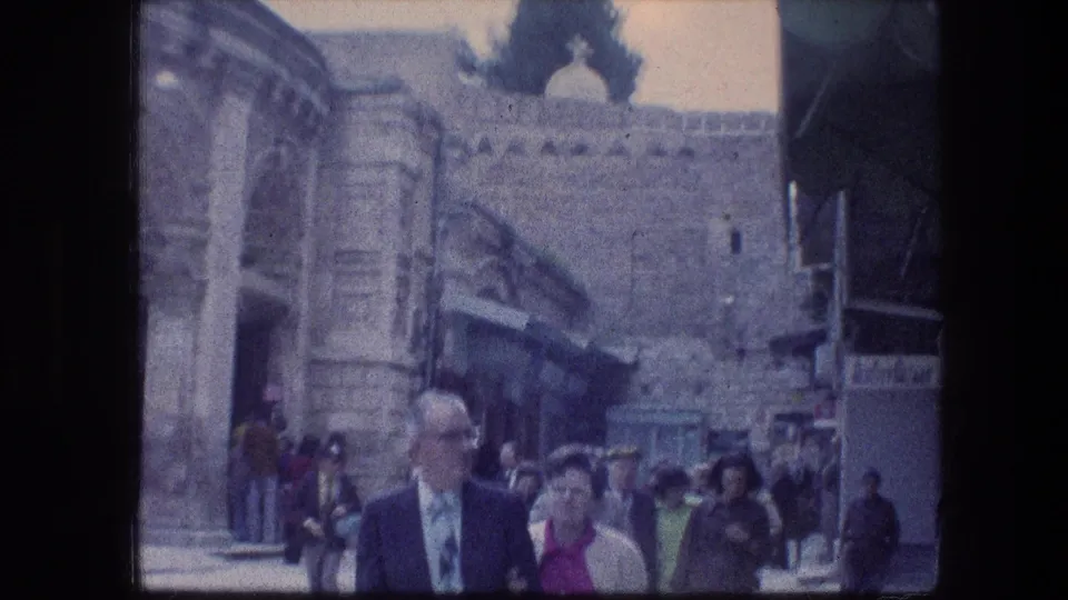 Tourists move through the Garden Tomb area in Jerusalem, with stone steps, walls, and an entrance visible in 1976 home-movie footage.
