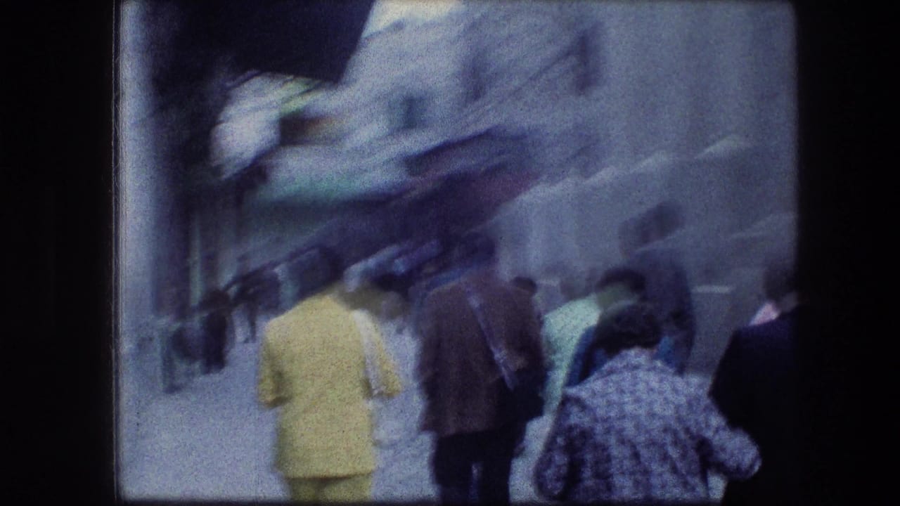 Adults walk away from the camera through a shaded Jerusalem street, including a person in a bright yellow jacket.